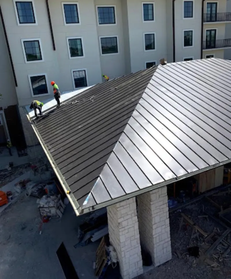 Crew installing standing seam metal roof panels on a commercial project in Carthage